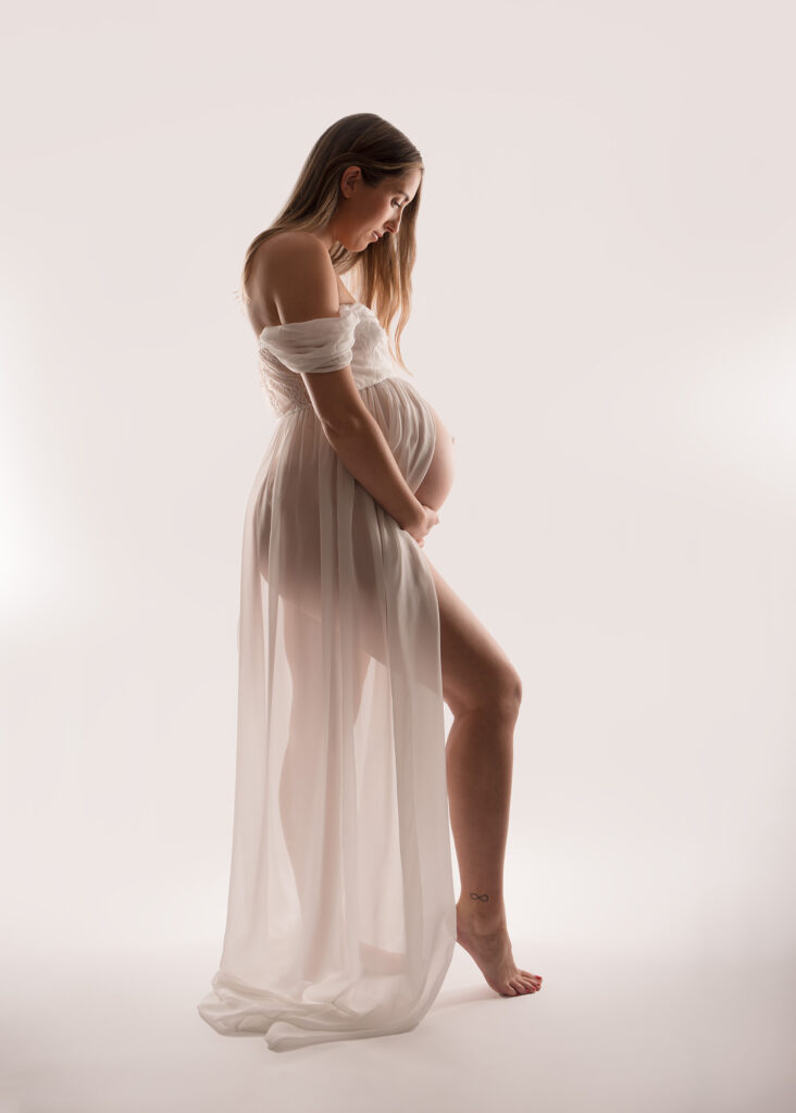 Modern maternity photoshoot image , backlit with chiffon dress.